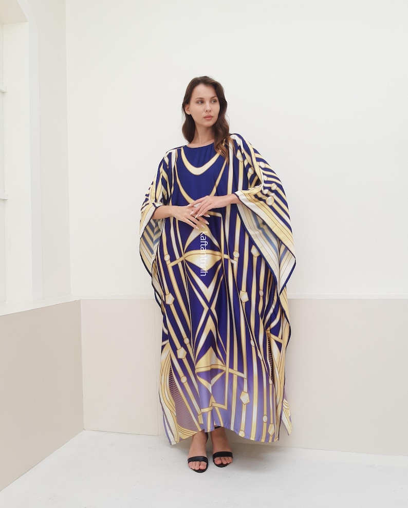 May include: A long, flowing blue and gold kaftan with a geometric pattern. The kaftan has a wide, flowing sleeve and a relaxed fit.