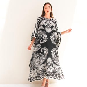 May include: A black and white patterned kaftan with a floral design. The kaftan has a long, flowing silhouette and a wide, open neckline.