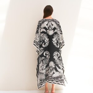 May include: A black and white maxi dress with a floral print. The dress has a loose, flowing silhouette and a V-neckline.