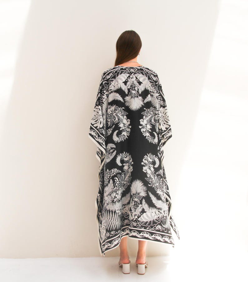 May include: A black and white maxi dress with a floral print. The dress has a loose, flowing silhouette and a V-neckline.