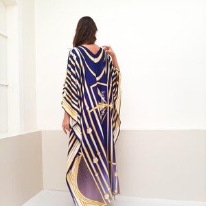 May include: A long, flowing kaftan with a geometric pattern in shades of blue, gold, and white. The kaftan has a V-neck and long sleeves.