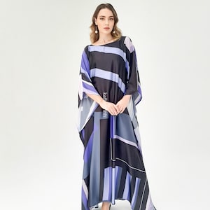 Può includere: Un abito lungo e fluido con un motivo geometrico in nero, viola, grigio e bianco. L'abito ha maniche ampie e una vestibilità ampia. La modella indossa tacchi color crema.