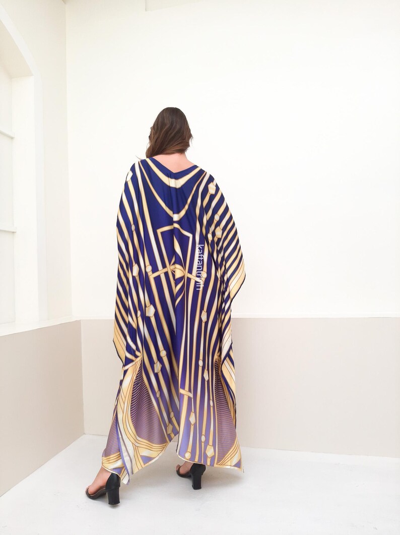 May include: A long, flowing blue and gold patterned kaftan with a V-neckline. The kaftan is made of a silky fabric and has a relaxed fit.
