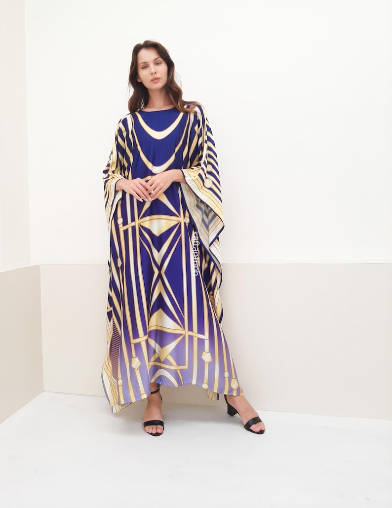 May include: A long, flowing blue and gold patterned kaftan with a wide, loose fit. The kaftan has a geometric design with stripes and squares.