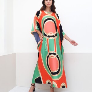 May include: A long, flowing, red, green, and black kaftan with a geometric pattern. The kaftan has a wide, flowing neckline and a loose, comfortable fit.