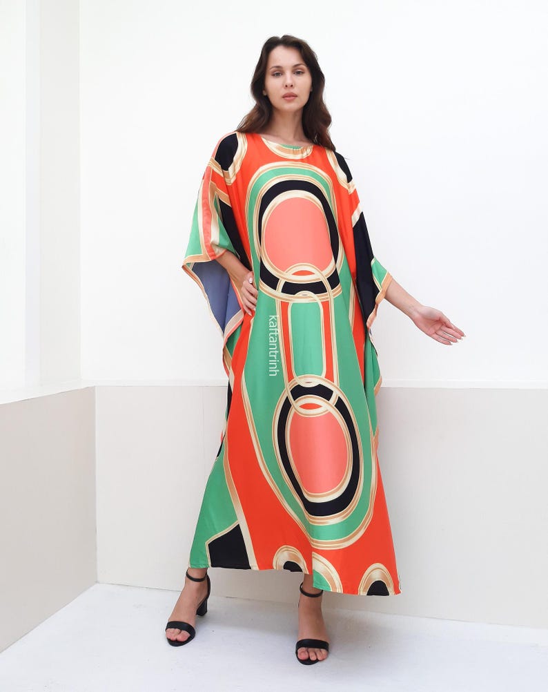 May include: A long, flowing, red, green, and black kaftan with a geometric pattern. The kaftan has a wide, flowing neckline and a loose, comfortable fit.