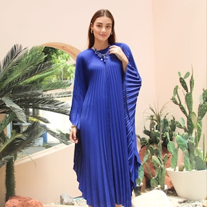 May include: A royal blue pleated maxi dress with long sleeves and a high neckline. The dress has a flowing, relaxed fit and is perfect for a summer evening.