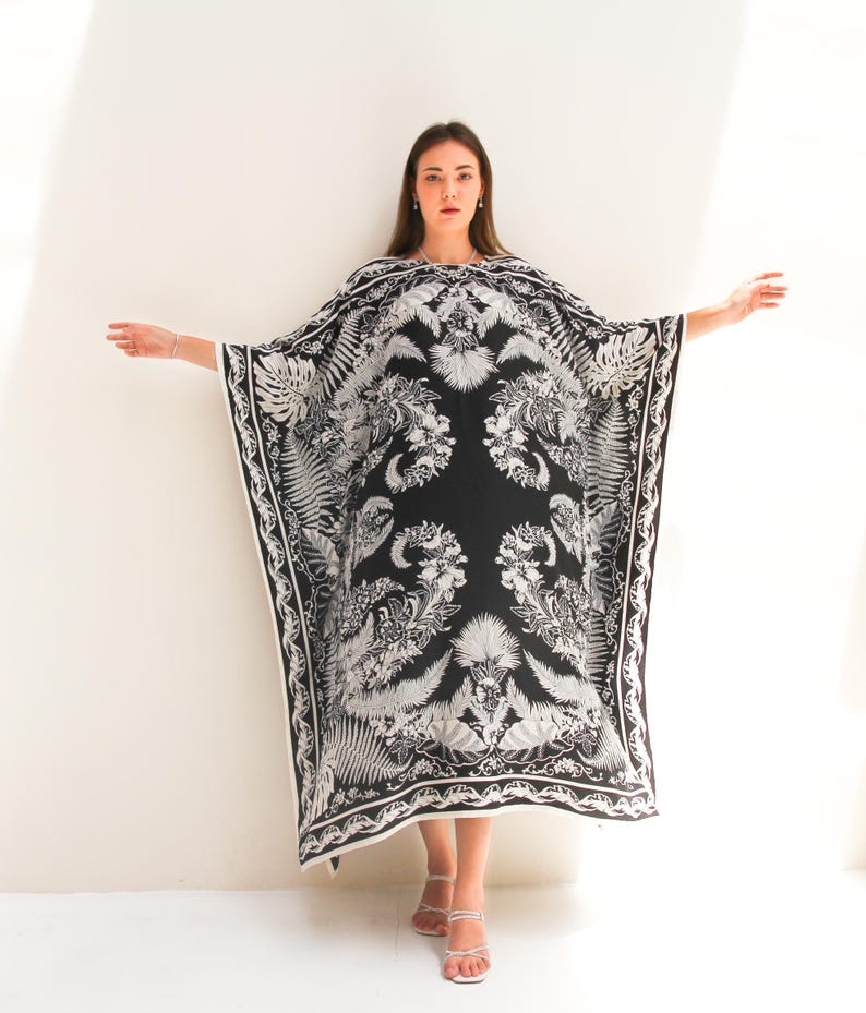 May include: A black and white kaftan with a floral print. The kaftan has a loose, flowing fit and is perfect for a summer day.