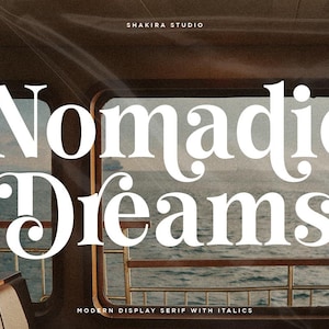 May include: A graphic design featuring the words "Nomadic Dreams" in a large, elegant white serif font. The text is set against a blurred background of a seascape, with the words "Shakira Studio" and "Modern Display Serif with Italics" also visible.