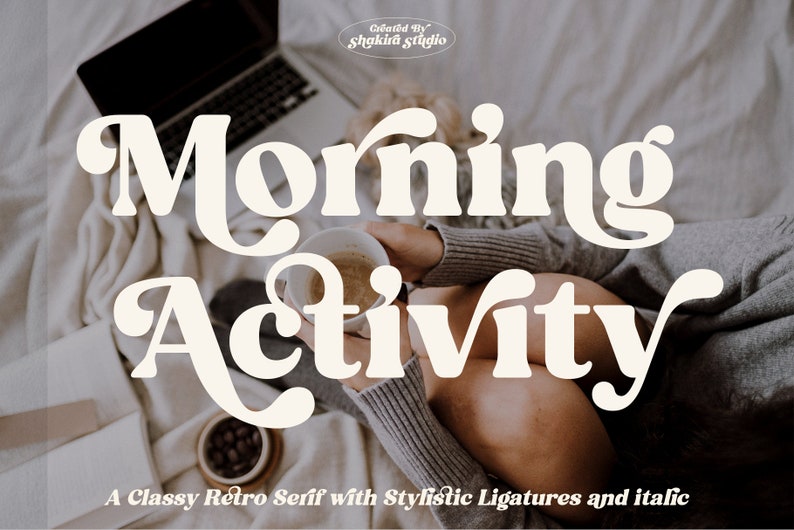 May include: A white retro font design with the text "Morning Activity" in a stylized font with ligatures. The text is on a background of a person sitting on a bed with a laptop and a cup of coffee.