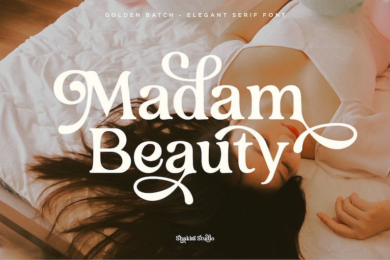 Op de afbeelding: Een vrouw ligt op een wit bed, met de woorden "Madam Beauty" in een groot, elegant schreeflettertype. De tekst "Golden Batch - Elegant Serif Font" staat bovenaan. De afbeelding heeft een zacht, warm kleurenpalet.