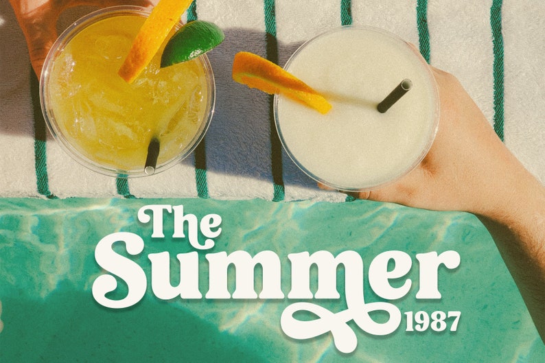 Op de afbeelding: Twee plastic bekers met rietjes en sinaasappelschijfjes, gevuld met gele en witte dranken, op een gestreepte handdoek met de tekst "The Summer of 1987" in witte letters.