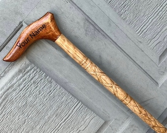 May include: A wooden walking stick with a carved handle. The handle is curved and has the words "Your Name" engraved on it. The stick has a braided design.
