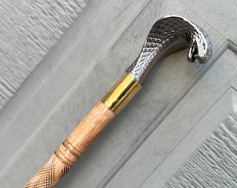 May include: A wooden walking stick with a carved design and a silver cobra head handle.