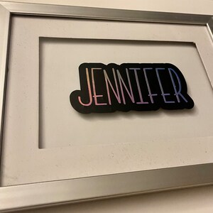 An example of the custom purple holographic name on a glass or acrylic frame.