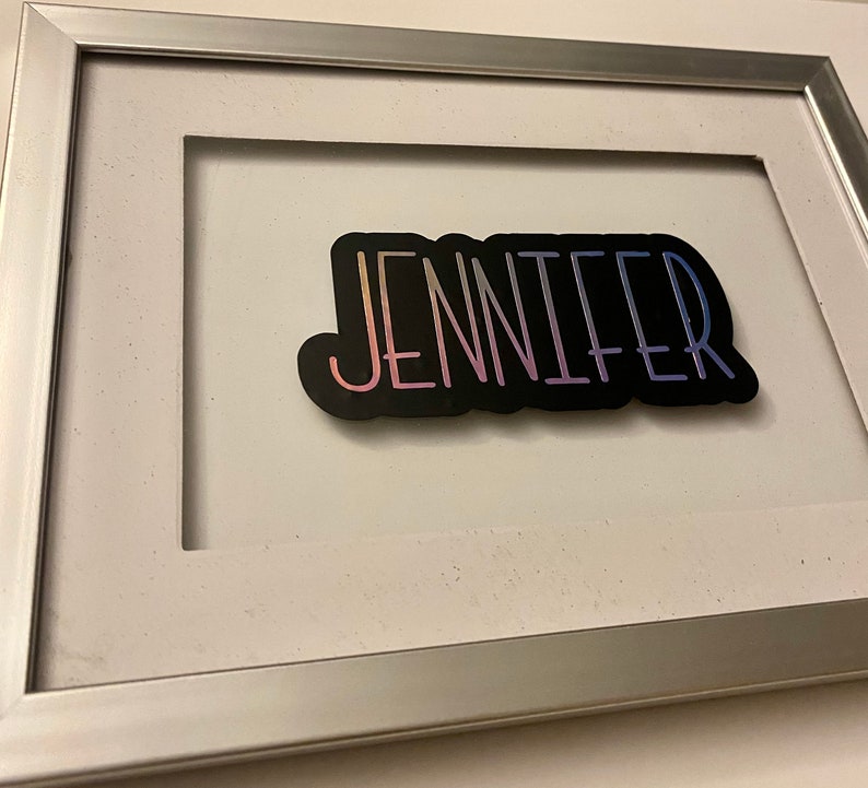 An example of the custom purple holographic name on a glass or acrylic frame.