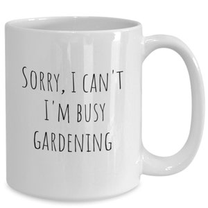 May include: White ceramic coffee mug with black text that reads "Sorry, I can't I'm busy gardening".