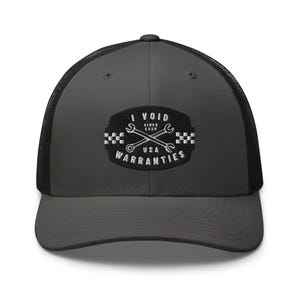 May include: A gray trucker hat with a black mesh back. The front features an embroidered patch with the text "I VOID SINCE EVER USA WARRANTIES" and crossed wrenches.