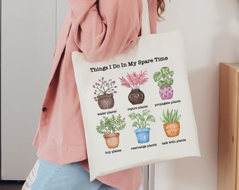 May include: A white tote bag with the text "Things I Do In My Spare Time" and illustrations of potted plants. The illustrations include water plants, report plants, propagate plants, buy plants, rearrange plants, and talk with plants.