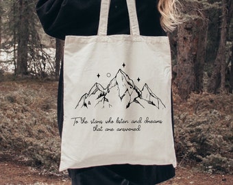 May include: A white canvas tote bag with black mountain and star illustrations and the text "To the stars who listen and dreams that are answered".