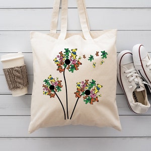 May include: A white canvas tote bag with a design of colorful cartoon bears arranged in the shape of dandelions. The bears are various shades of pink, green, yellow, and orange.