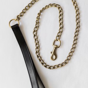 May include: A black leather dog lead with a gold chain and a gold clasp.
