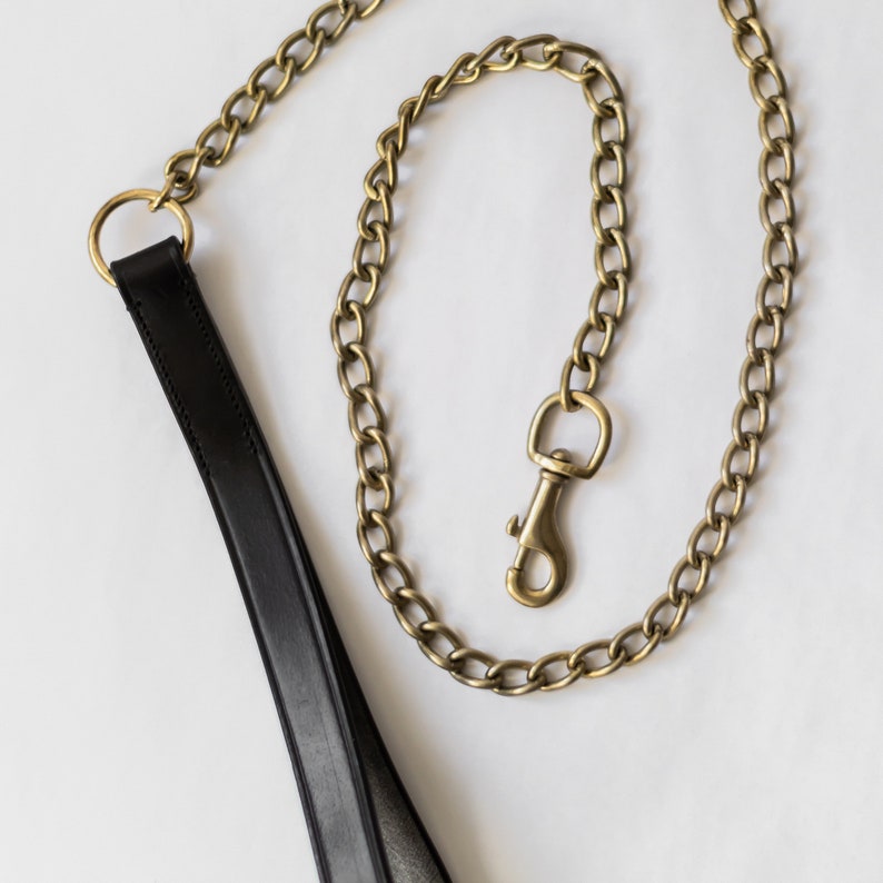 May include: A black leather dog lead with a gold chain and a gold clasp.