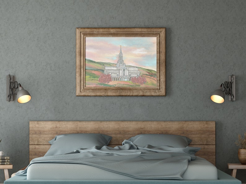 Peut inclure: Une peinture encadr&eacute;e repr&eacute;sentant un b&acirc;timent blanc avec une fl&egrave;che, entour&eacute; d'arbres et de collines. Le ciel est d'un rose et d'un bleu doux. La peinture est accroch&eacute;e &agrave; un mur gris au-dessus d'une t&ecirc;te de lit en bois.
