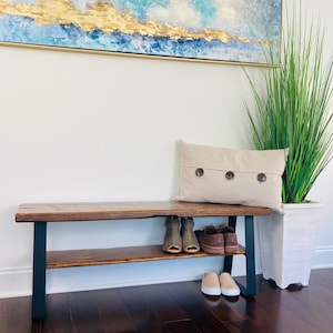 May include: A wooden bench with a black metal frame and a shelf for storing shoes. The bench has a rustic, farmhouse style and is perfect for an entryway or mudroom.