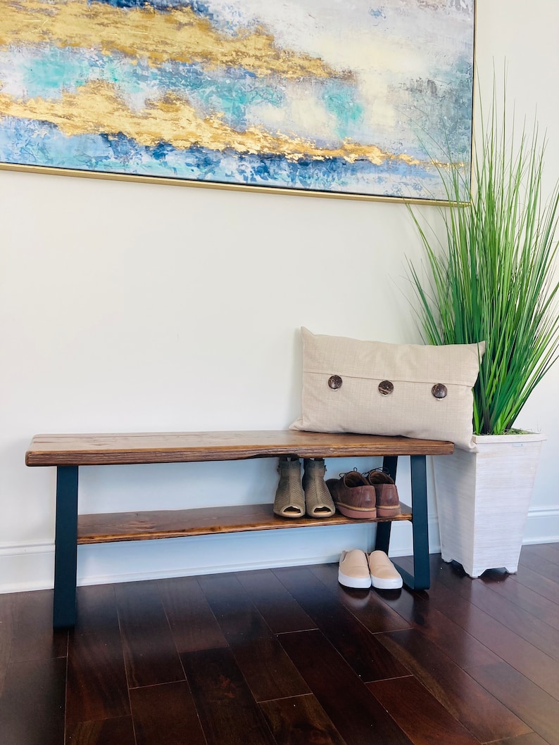May include: A wooden bench with a black metal frame and a shelf for storing shoes. The bench has a rustic, farmhouse style and is perfect for an entryway or mudroom.