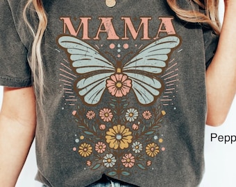 May include: A gray t-shirt with a vintage-style butterfly graphic and the word "MAMA" printed on it. The butterfly is surrounded by flowers in shades of pink, yellow, and blue.