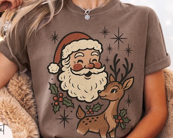 May include: Espresso-colored t-shirt featuring a vintage-style Santa Claus and reindeer graphic. The design includes a smiling Santa with a white beard and a reindeer with holly accents. The shirt is part of a Christmas-themed apparel collection.