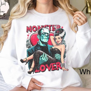 Peut inclure: Sweat-shirt blanc avec un imprim&eacute; graphique de Frankenstein et sa fianc&eacute;e. Le graphique pr&eacute;sente un c&oelig;ur rouge et le texte "Monster Lover".