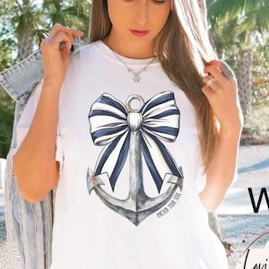 May include: White t-shirt with a blue and white anchor and bow design. The text "Anchor Your Soul" is printed below the design.