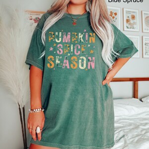 Może przedstawiać: Zielony, duży T-shirt z napisem "Pumpkin Spice Season" w kolorze r&oacute;żowym, pomarańczowym i ż&oacute;łtym z białymi gwiazdkami.