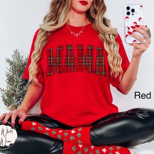May include: A red t-shirt with the word "MAMA" in a plaid pattern across the chest. The word "Red" is printed in white on the bottom right of the image. The person is wearing black leggings and red socks.
