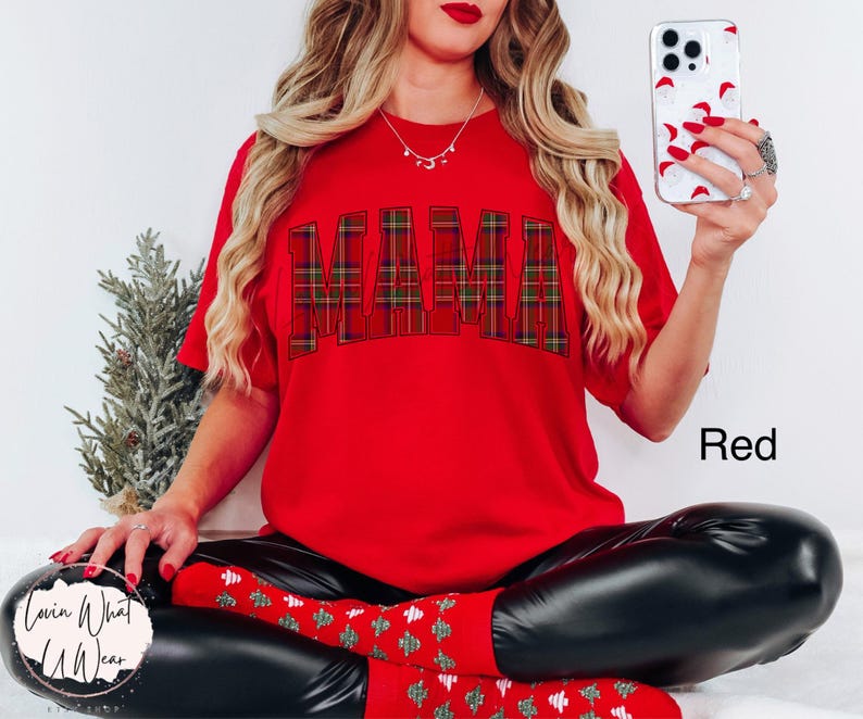 May include: A red t-shirt with the word "MAMA" in a plaid pattern across the chest. The word "Red" is printed in white on the bottom right of the image. The person is wearing black leggings and red socks.