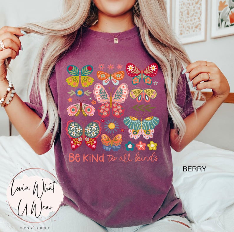 May include: Purple t-shirt with a colorful butterfly design and the text "Be Kind to all kinds".