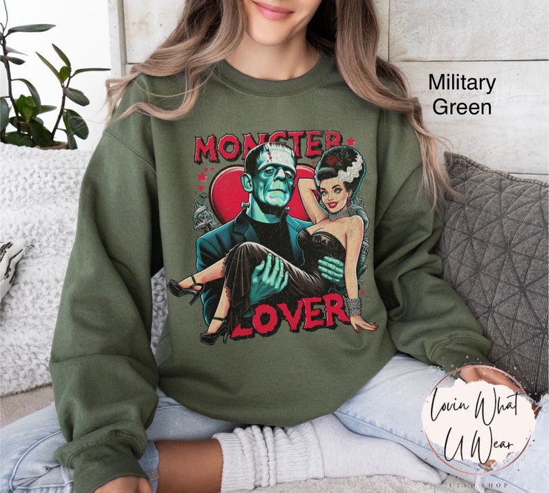 Peut inclure: Un sweat-shirt vert avec un imprim&eacute; graphique d'un couple de monstres. Le texte sur le sweat-shirt dit "Monster Lover".