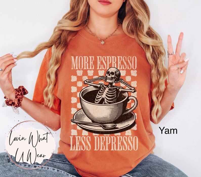 May include: A burnt orange t-shirt with a graphic of a skeleton in a coffee cup. The text on the shirt reads "More Espresso Less Depresso".