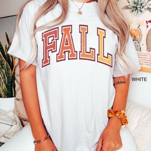 May include: White t-shirt with a vintage-style "FALL" graphic in orange, red, and yellow.