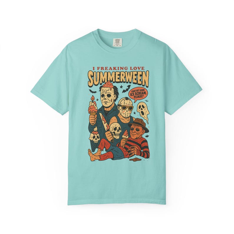 May include: A pale blue t-shirt with a cartoon graphic of horror movie characters enjoying ice cream. The text on the shirt says "I Freaking Love Summerween" and "Can I get some ice cream please?"