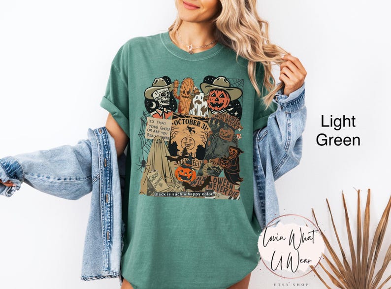 May include: Light green t-shirt with a Halloween-themed graphic. The design includes a skeleton, a pumpkin head, and the text "October 31". The shirt also features a ghost, a spider web, and the phrase "Halloween Never Die".