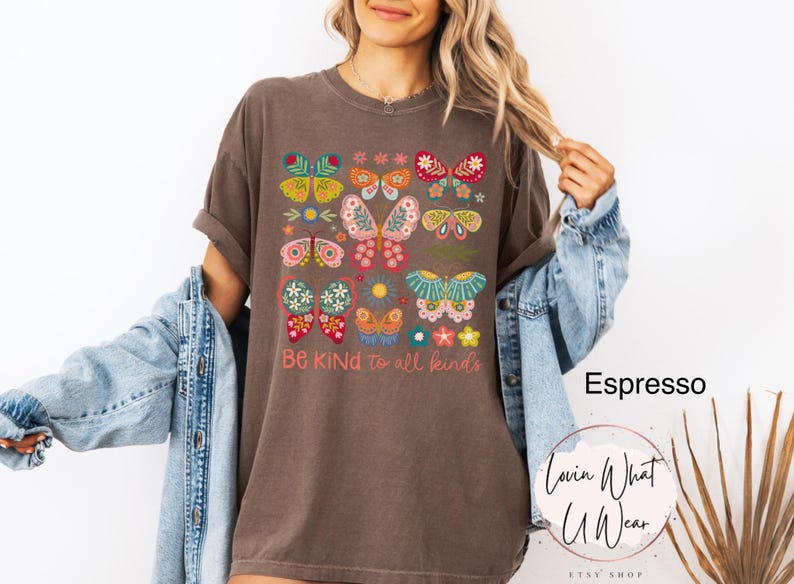 May include: A brown t-shirt with a graphic of colorful butterflies and flowers. The text "Be Kind to all kinds" is printed below the graphic.