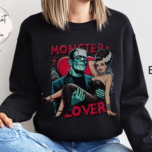 Peut inclure: Sweat-shirt noir avec un imprim&eacute; graphique de Frankenstein et sa fianc&eacute;e. Le texte "Monster Lover" est imprim&eacute; sous l'image.