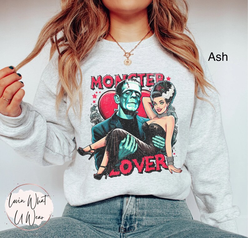 Peut inclure: Un sweat-shirt gris avec un imprim&eacute; graphique de Frankenstein et une femme en robe noire. Le graphique dit "Monster Lover" et pr&eacute;sente un c&oelig;ur rouge.