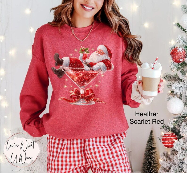 May include: Heather scarlet red sweatshirt with a graphic of Santa Claus relaxing in a martini glass. The image includes a red bow and the text "Lovin What U Wear" and "Heather Scarlet Red".