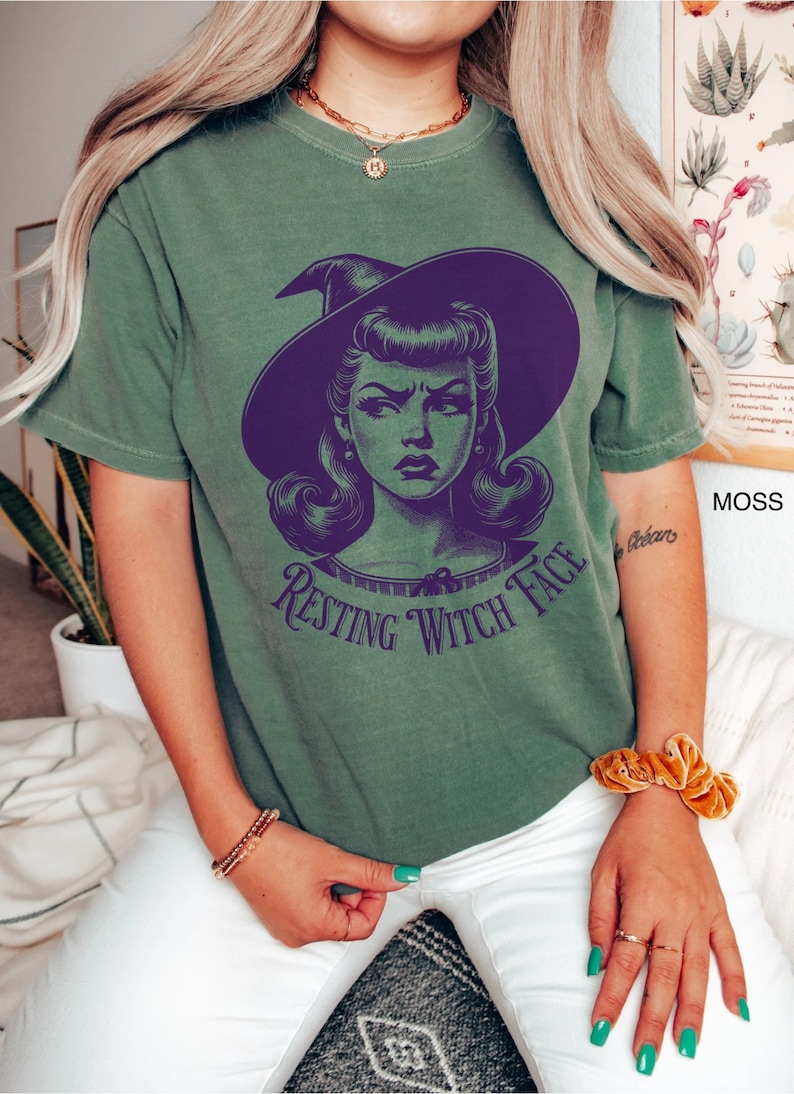 May include: Green t-shirt with a purple illustration of a witch with a hat and the text "Resting Witch Face".