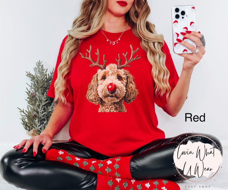 K&ouml;nnte beinhalten: Rotes T-Shirt mit einem Aufdruck eines Hundes, der ein Rentiergeweih und eine rote Nase tr&auml;gt. Der Text "Lovin What U Wear" ist in der rechten unteren Ecke des Bildes zu sehen.