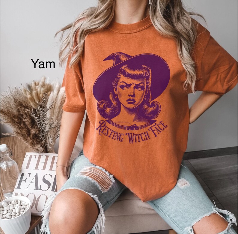 May include: Orange t-shirt with a purple witch graphic and the text "Resting Witch Face".